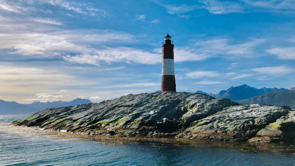 A lighthouse stands against the dramatic Patagonian landscape