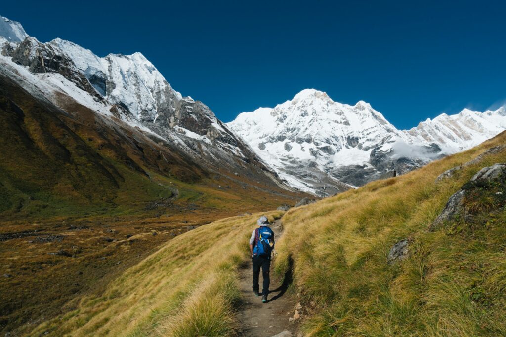 A hiker on a grassy footpath through the mountains